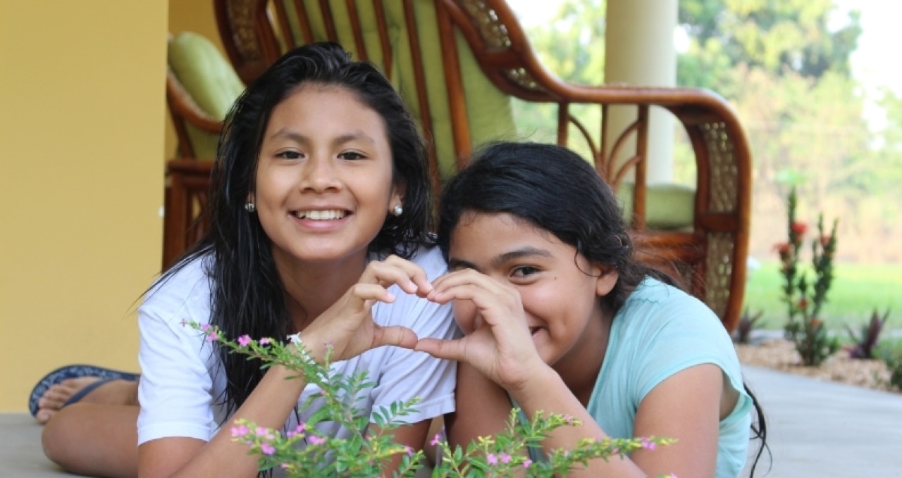 two girls making a heart with their hands